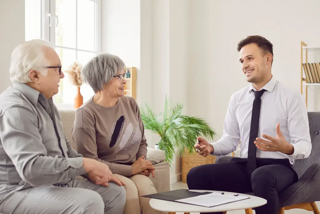 Friendly senior care advisor cheerfully discussing planning options and reviewing documents with a smiling senior couple.